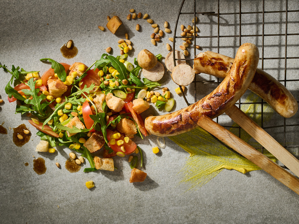 Grillwurst vom Strohschwein auf buntem Brotsalat
